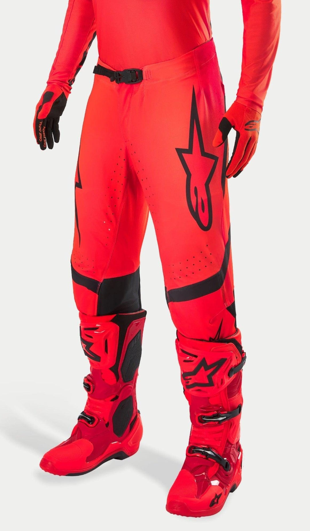 Pantaloni da motocross Alpinestars Supertech Ember LE, rosso fluo e rosso acceso con dettagli neri, indossati con stivali e guanti da corsa rossi coordinati, caratterizzati da un logo a stella nero sulla gamba, fibbia sicura in vita e zone traforate per la ventilazione.